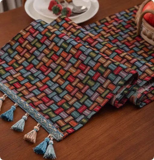 Long decorative table runner with handwoven tassels in a blue ginkgo leaf pattern on a wooden table.