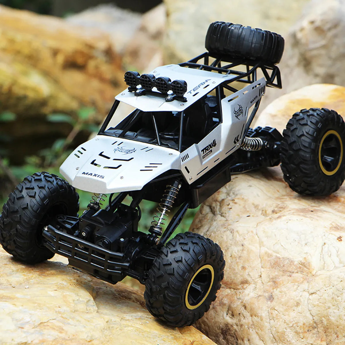 Large black and silver 4WD remote control off-road climbing cars with wireless controller on a rocky surface.