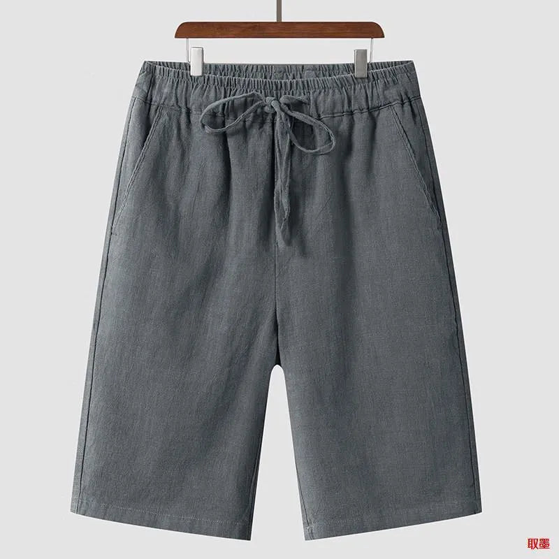 Men's beige linen casual shorts with loose cropped fit and elastic waistband on a neutral background.