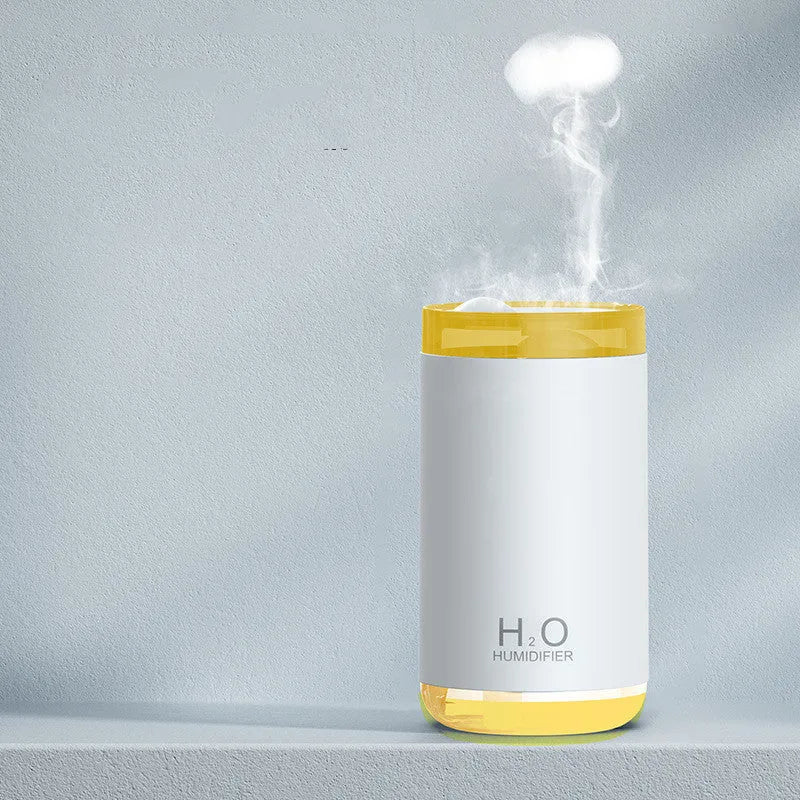 White jellyfish-shaped USB humidifier emitting smoke ring mist with warm night light glow on a table.