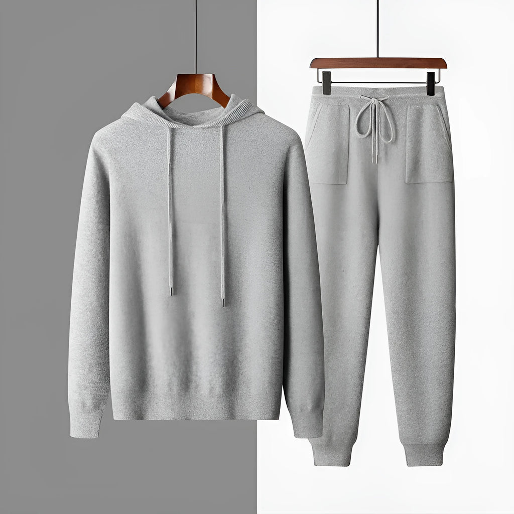Man wearing a light grey hooded cashmere sweatshirt and matching long pants from a winter leisure set.