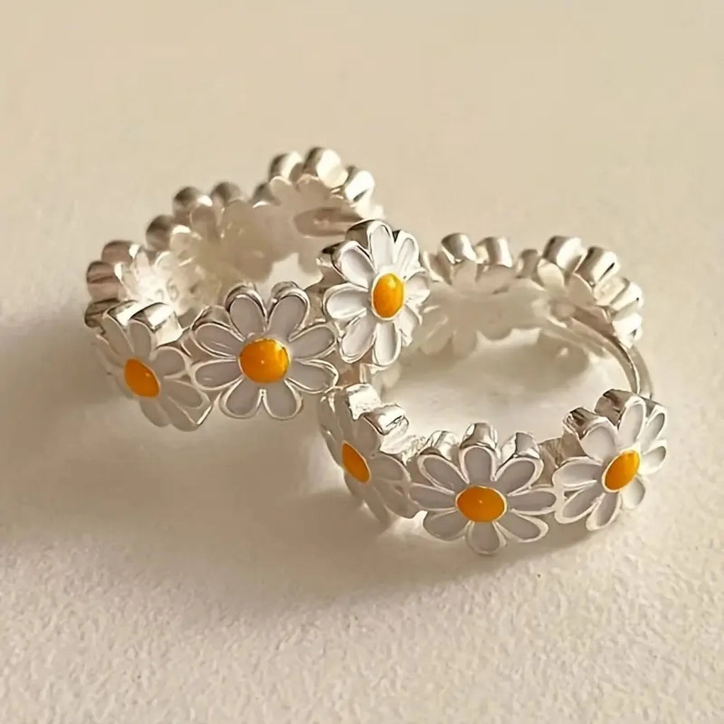 White daisy flower fashion ring earrings with platinum-set gems on a model.