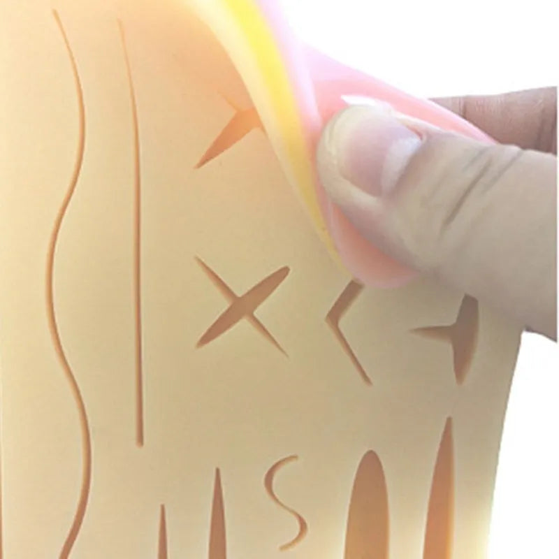 Medical student training kit with black silicone suture pad, tools, and multi-wound block on a table