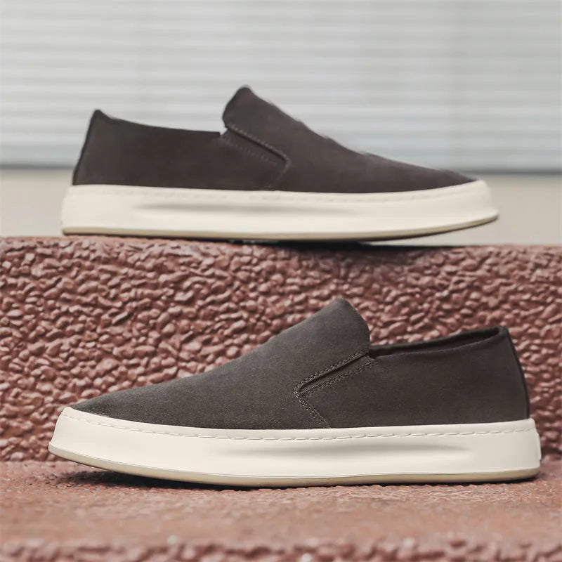 Men's grey slip-on casual shoes with round toe, mid-heel, and visible stitching on a rubber sole.