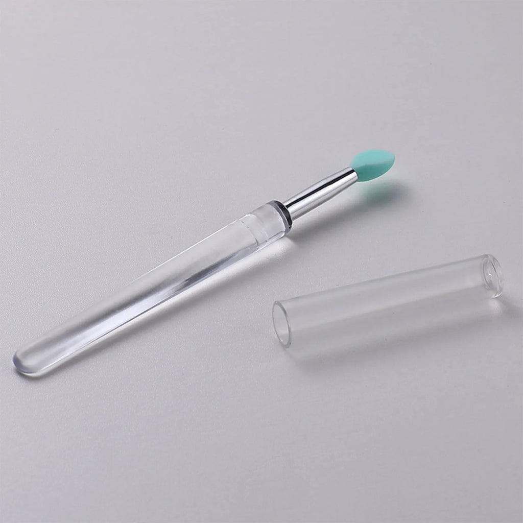 Set of eight coloured reusable silicone lip brushes with protective caps on a white background.