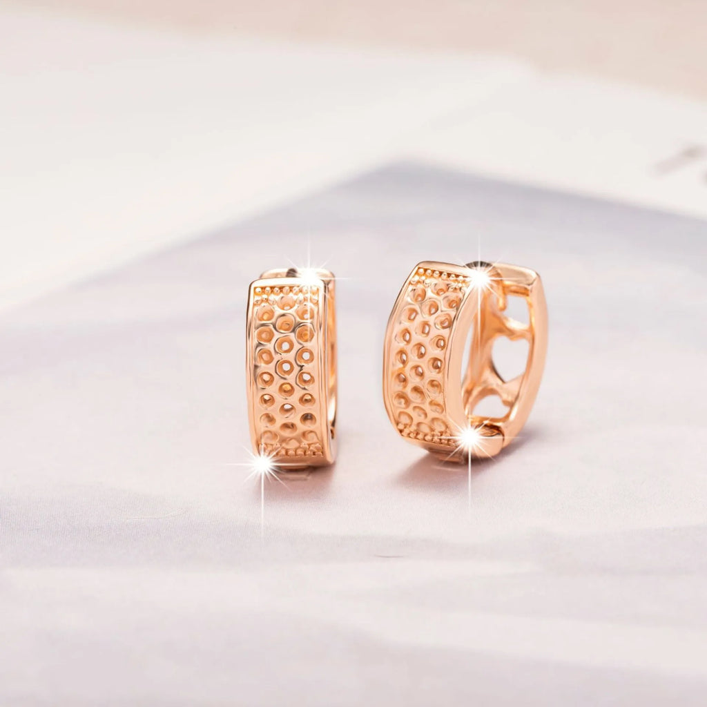 Rose gold heart-shaped women's earrings with three hollowed out sections in a circular design.