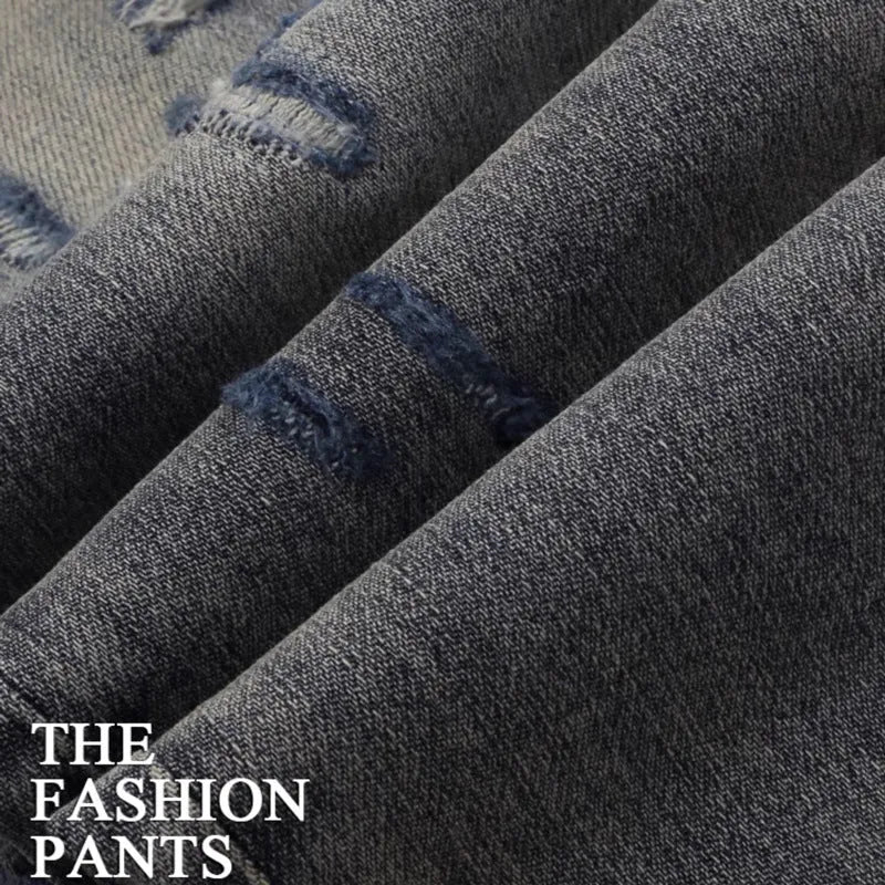 Slim fit blue jeans with distressed hole patches and embroidery on the legs, showing a washed-out colour.