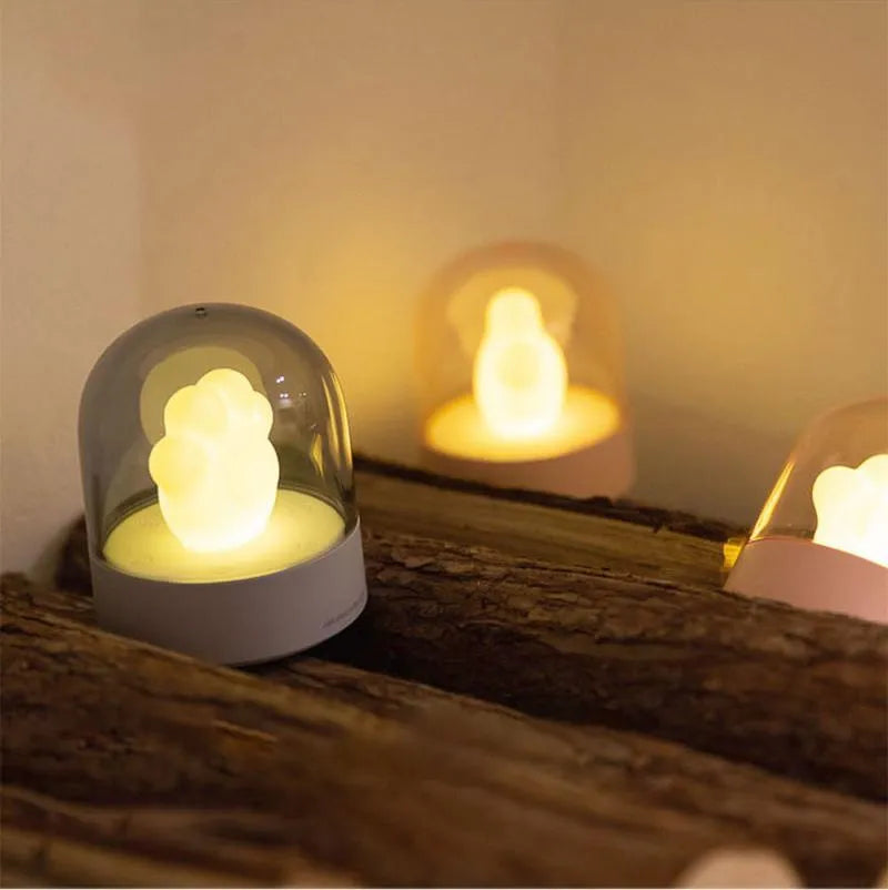 Grey cat paw shaped USB night light with rotating soft light and music box function on wooden desk