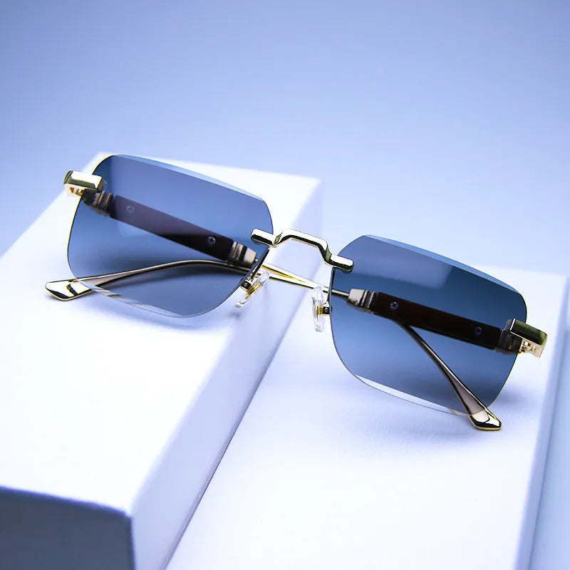 Frameless edge-cut sunglasses with gold frame, wood grain legs, and gradient grey lenses on a neutral background
