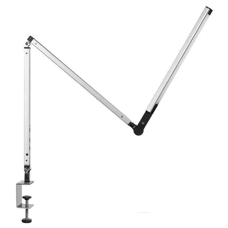 A black foldable LED desk lamp with a metal clip attached to a wooden desk edge, remote control nearby.