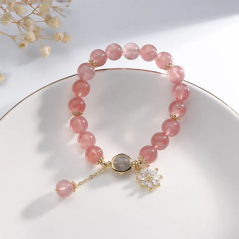 Mori style crystal bracelet with strawberry quartz stones and floral design details on a wrist.