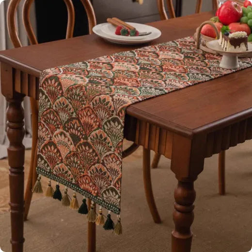 Long decorative table runner with handwoven tassels in a blue ginkgo leaf pattern on a wooden table.