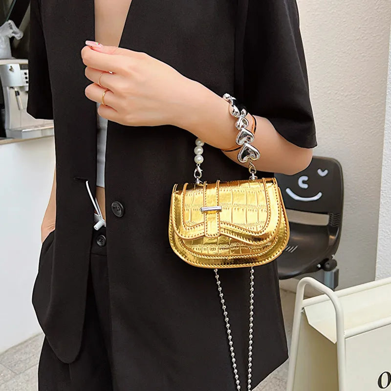 Silver laser pearl tote saddle girl mini crossbody bag with single strap on a mannequin.