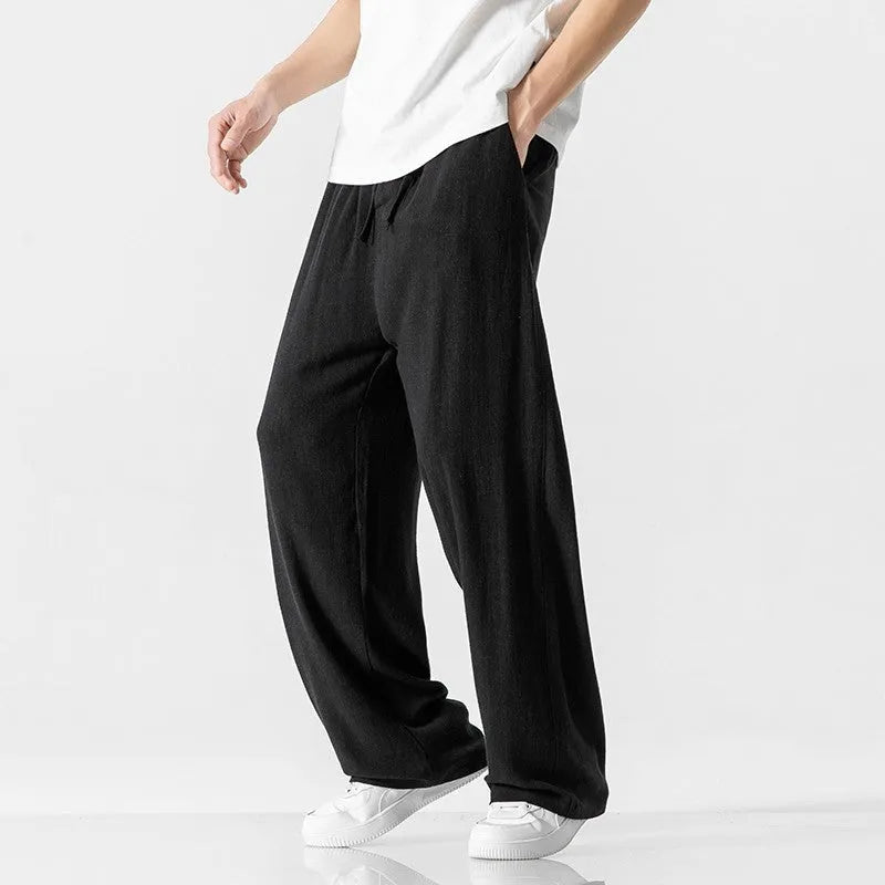 Man modelling beige linen drawstring trousers with a straight-leg cropped fit.