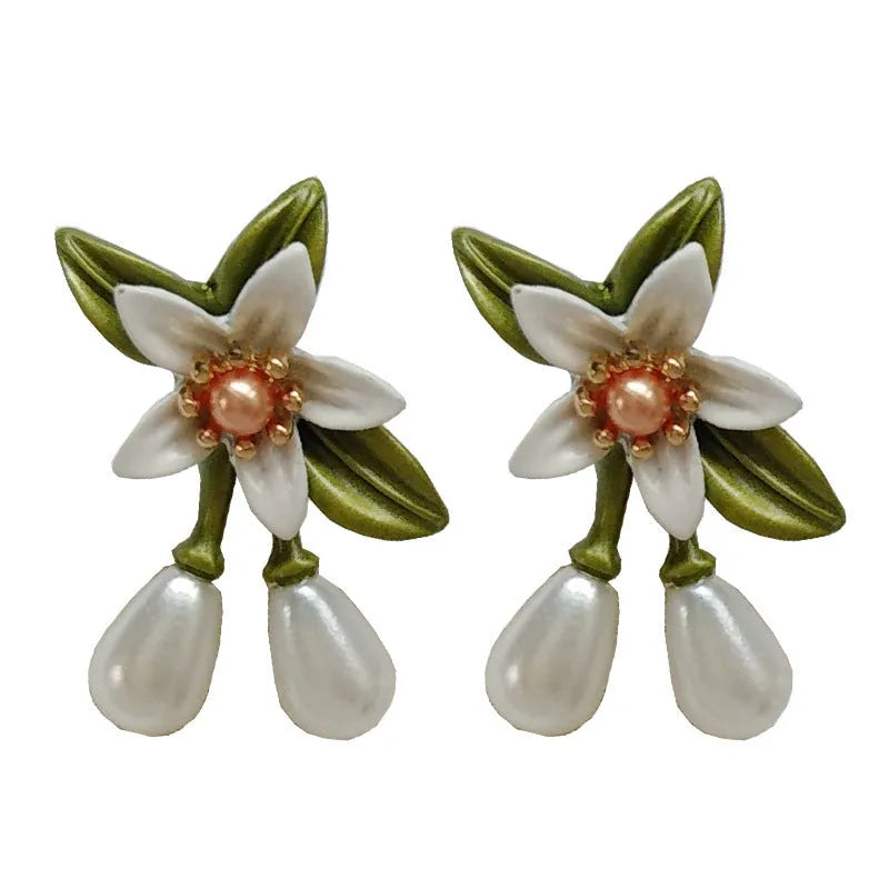 Close-up of women's camellia flower ear clip earrings with sterling silver needle accents on a contrasting background.