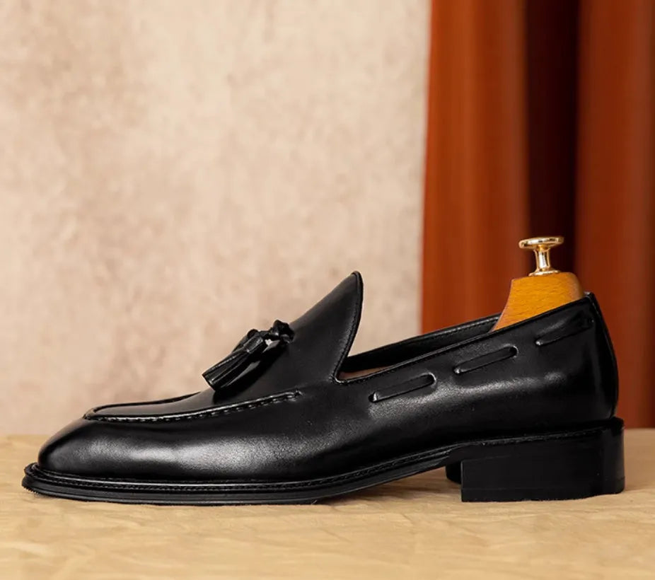 Men's black genuine leather slip-on loafers showing polished finish and rubber sole