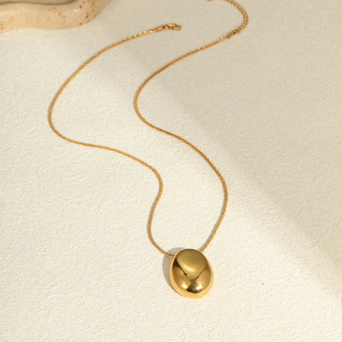 Geometric gold-plated pendant necklace with adjustable chain on white background