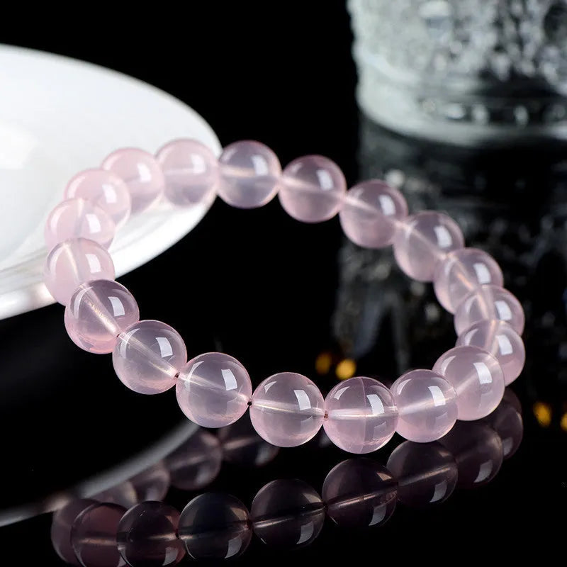A polished natural starlight crystal bead bracelet in pink, shown as a single circle.