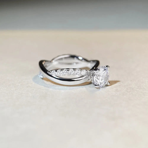 Silver ring with twisted arm design and a 1 karat moissanite stone in a four-claw setting.