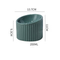 A dark green ceramic elevated cat bowl with a tilted, round design on a wooden surface.