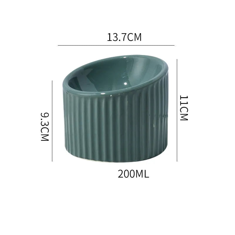 A dark green ceramic elevated cat bowl with a tilted, round design on a wooden surface.