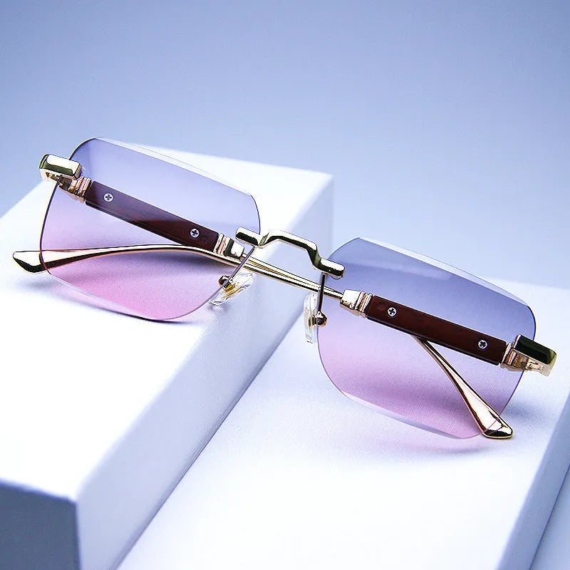 Frameless edge-cut sunglasses with gold frame, wood grain legs, and gradient grey lenses on a neutral background