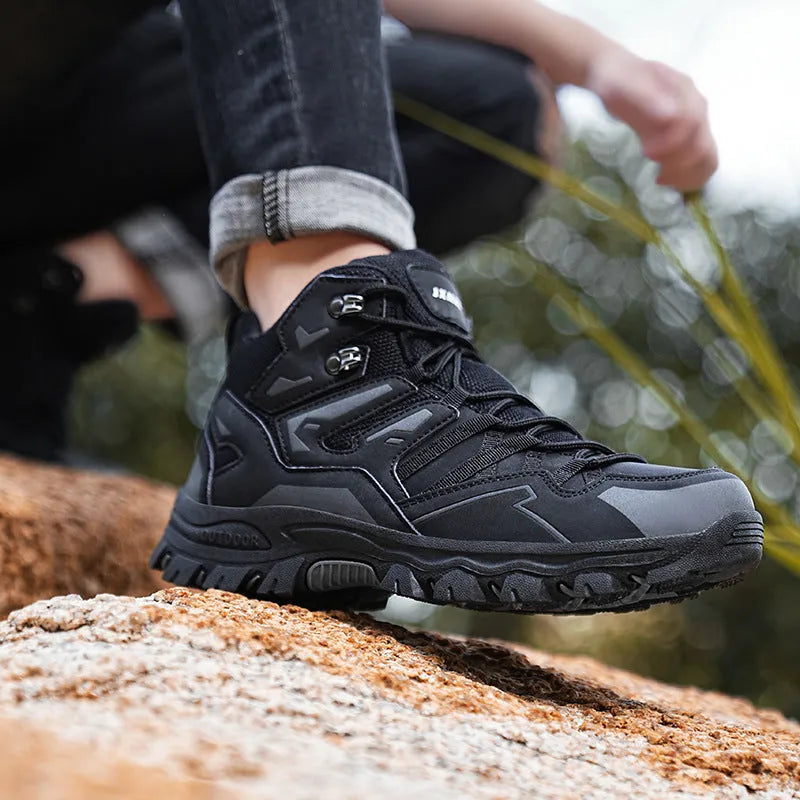 A pair of low-top hiking sneakers with a flannel upper and rubber sole, shown on a rocky mountain path.