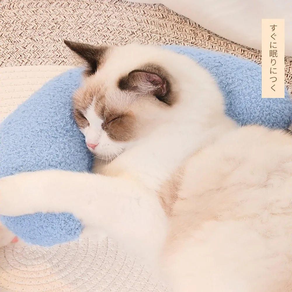 Blue U-shaped cat pillow with an adjustable fabric collar on a grey sofa.