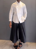 White asymmetrical front long sleeve shirt paired with black pleated trousers in a women's two-piece set.