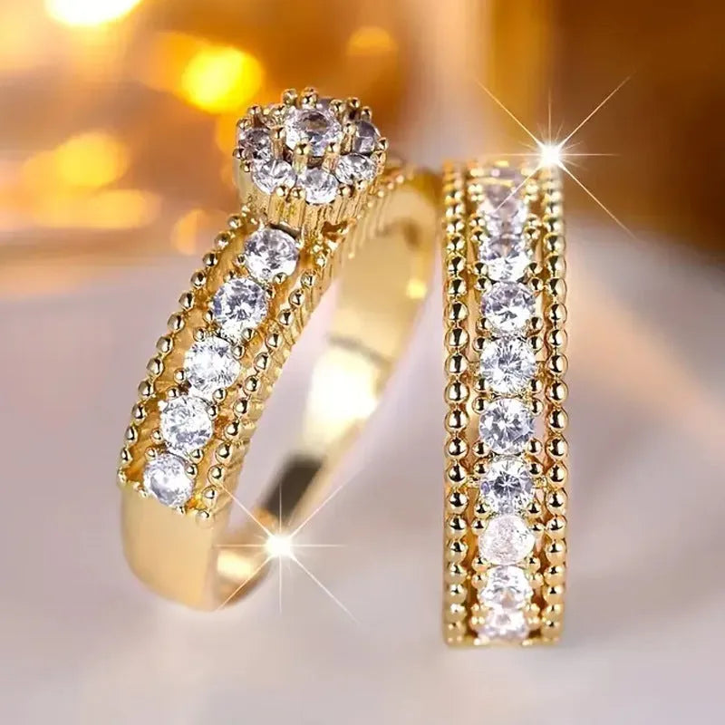 Two geometric gold electroplated zinc alloy rings on a flat surface