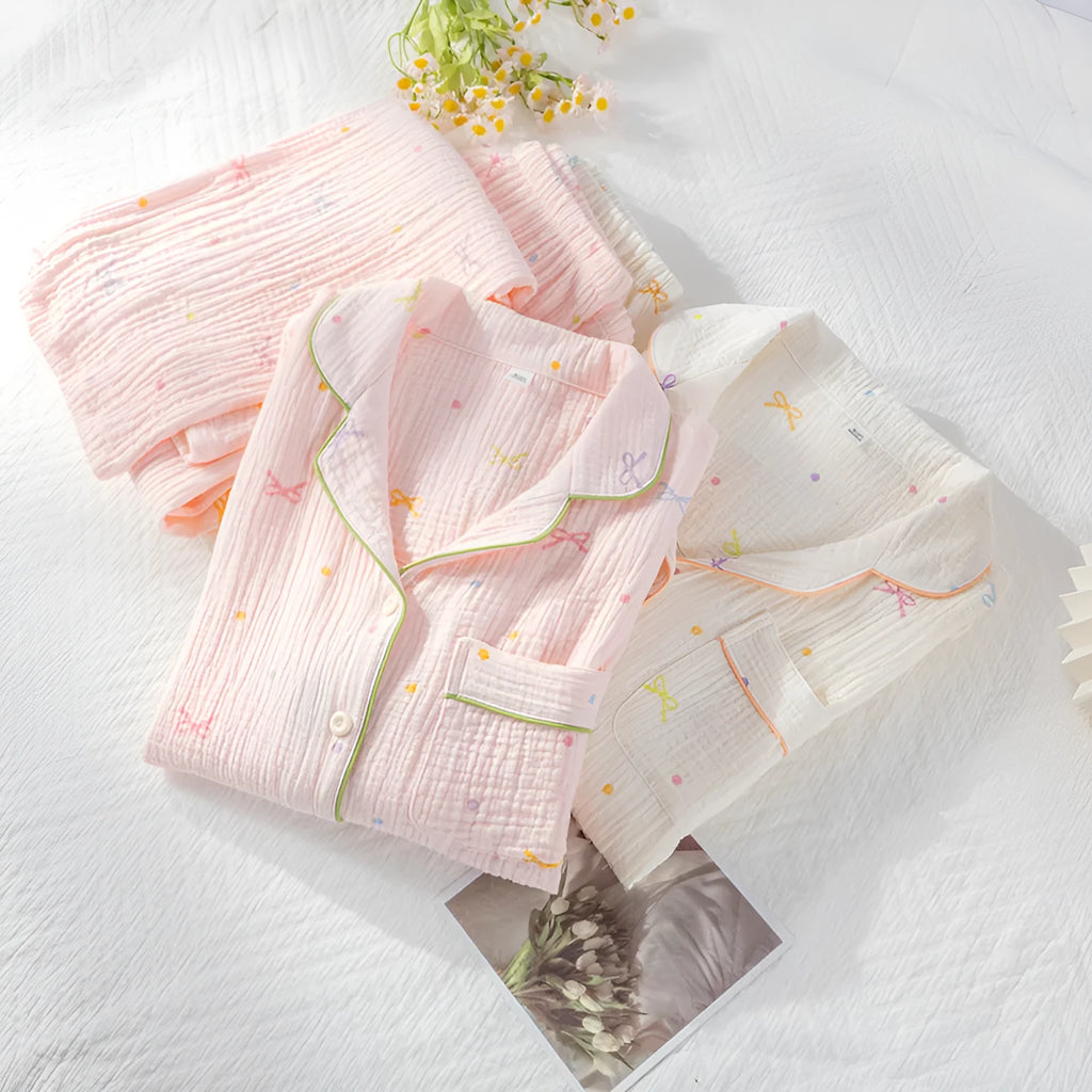 Women's pink cotton crepe pajama suit with long sleeves and trousers laid flat.