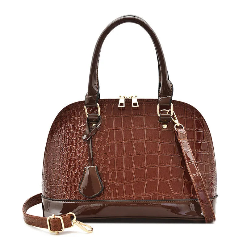 Large shiny black PU leather crossbody bag showing structured shell shape and shoulder strap.