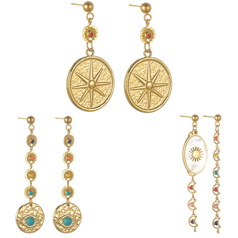 A pair of stainless steel geometric earrings showing star, eye, and shell sun designs.