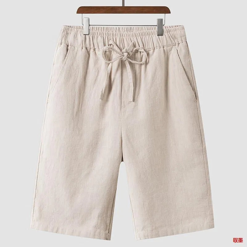 Men's beige linen casual shorts with loose cropped fit and elastic waistband on a neutral background.