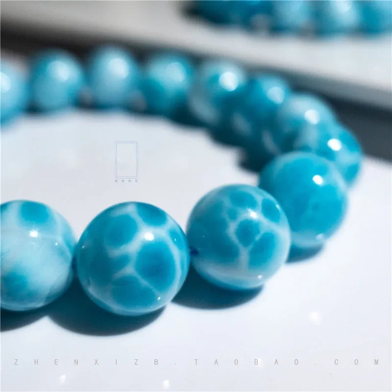 Blue Bodhi bead bracelet with a natural crystal sea-pattern stone charm on a wrist.