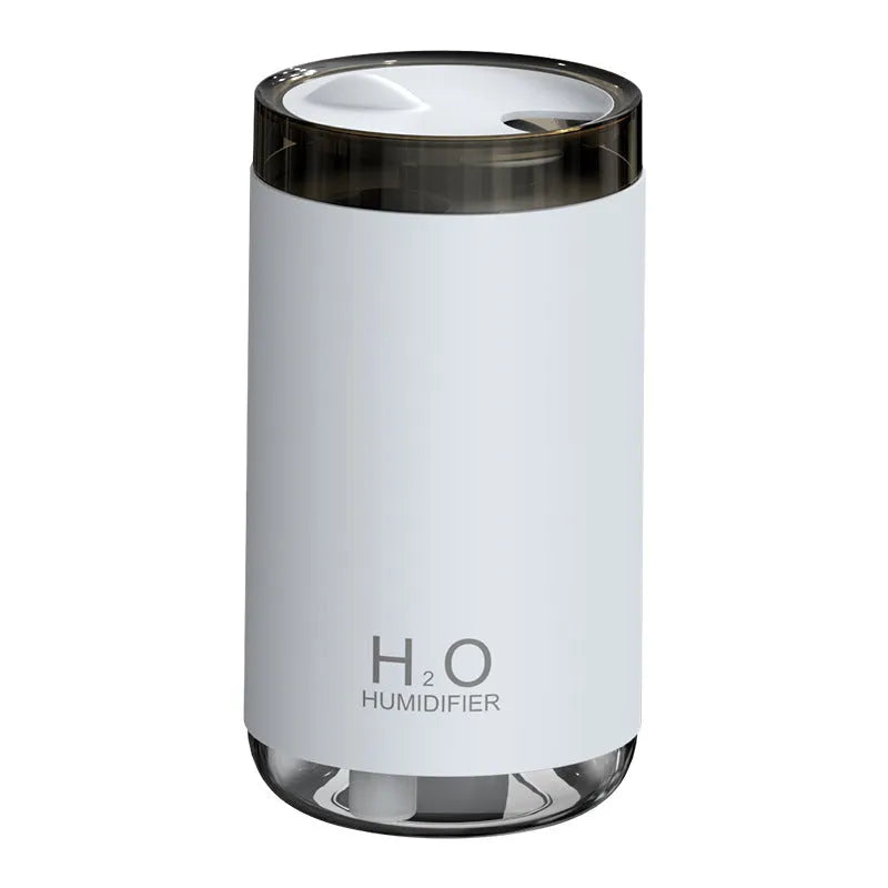 White jellyfish-shaped USB humidifier emitting smoke ring mist with warm night light glow on a table.