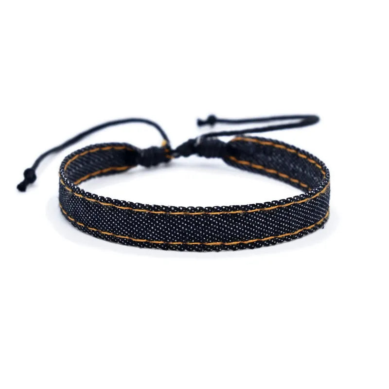 Handmade denim fabric bracelet carrying strap in national style on wrist, showing charm attachment point.