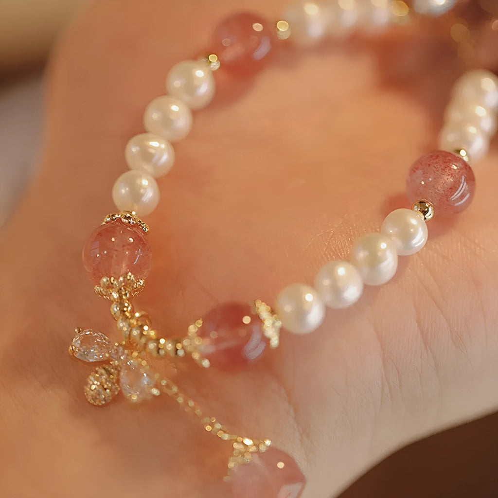 Women's handmade strawberry quartz and crystal bracelet with a decorative bow on a string of beads.