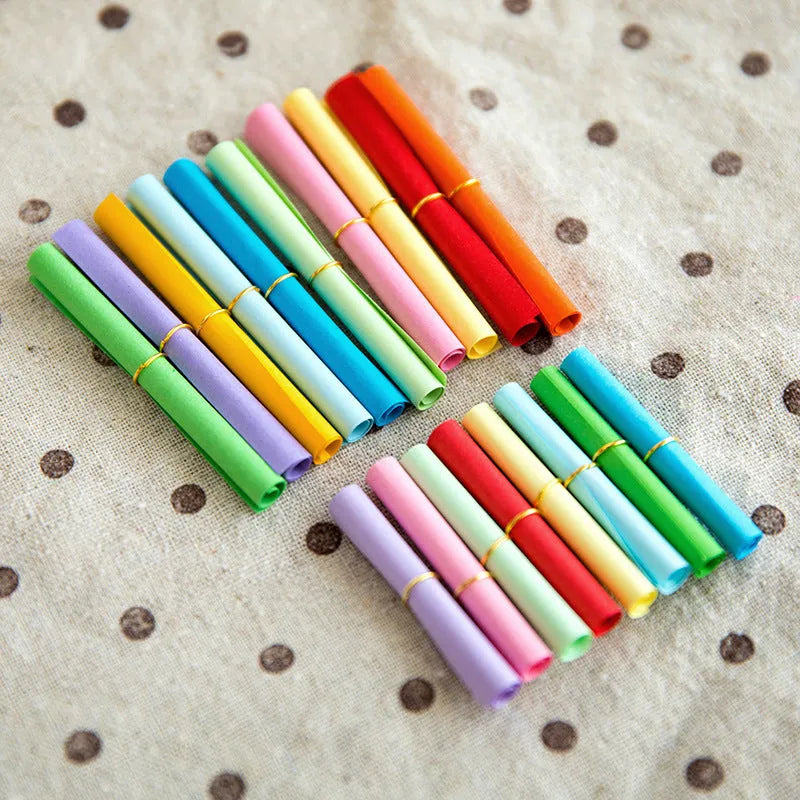 Assorted coloured mini paper scrolls with metal eyelets in sizes 3x7cm, 4x7cm, 5x5cm and 7x7cm.