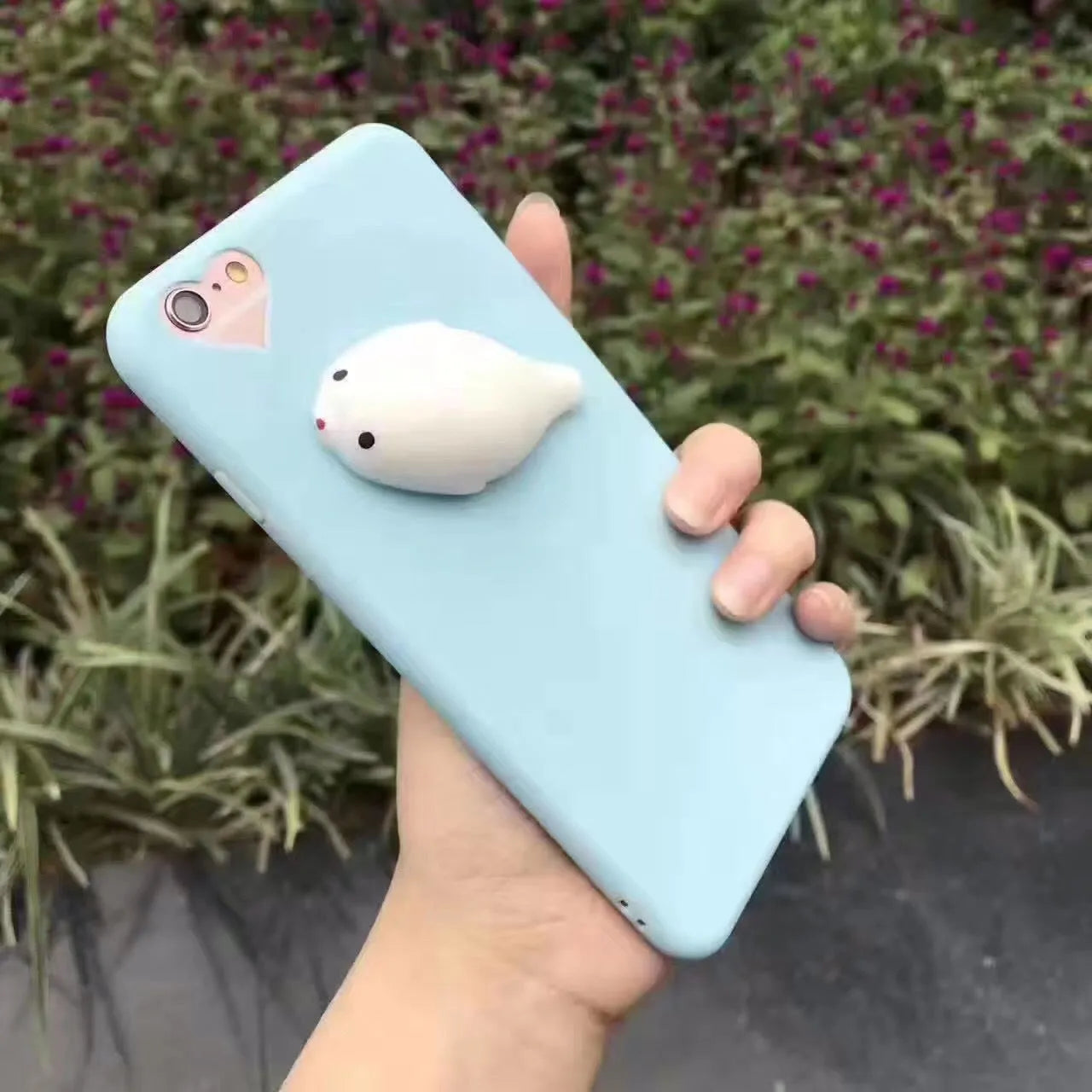 A soft pink silicone iPhone case featuring a raised 3D cartoon cat design on the back.