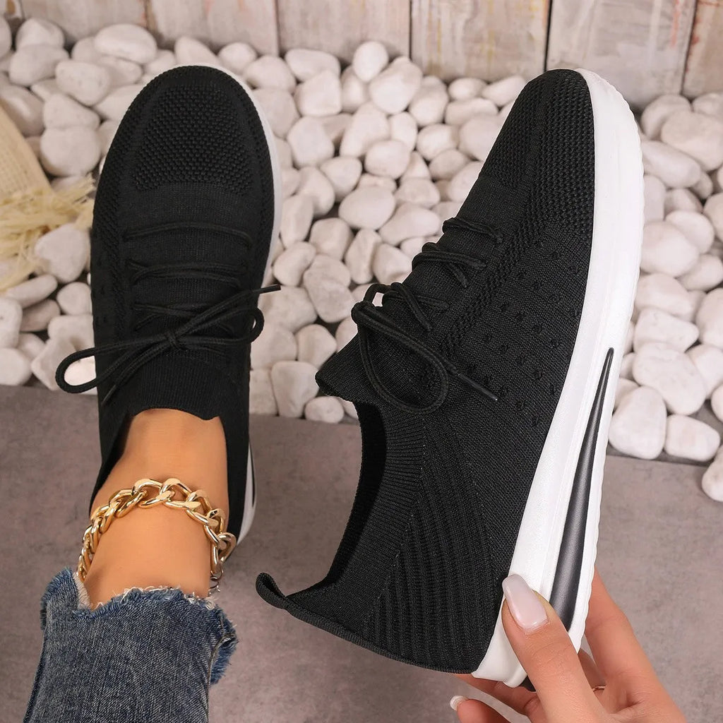 Women's black fly-knit casual sneakers with low-top design and round toe.