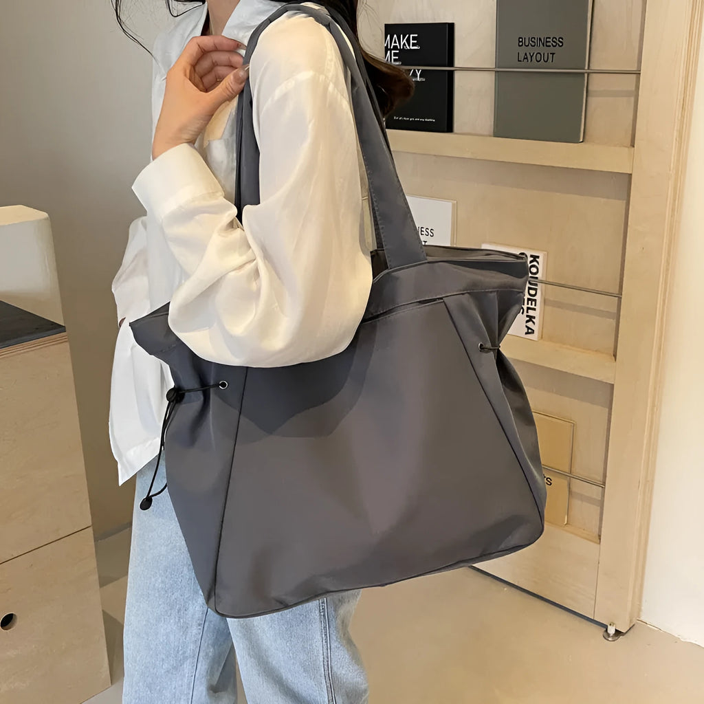 Soft Oxford cloth folding commuter tote bag shown in one of five colours: black, brown, dark grey, light grey or purple.