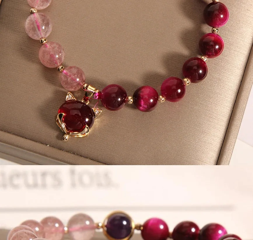 Simple bracelet with a red strawberry crystal on a black elastic rope.