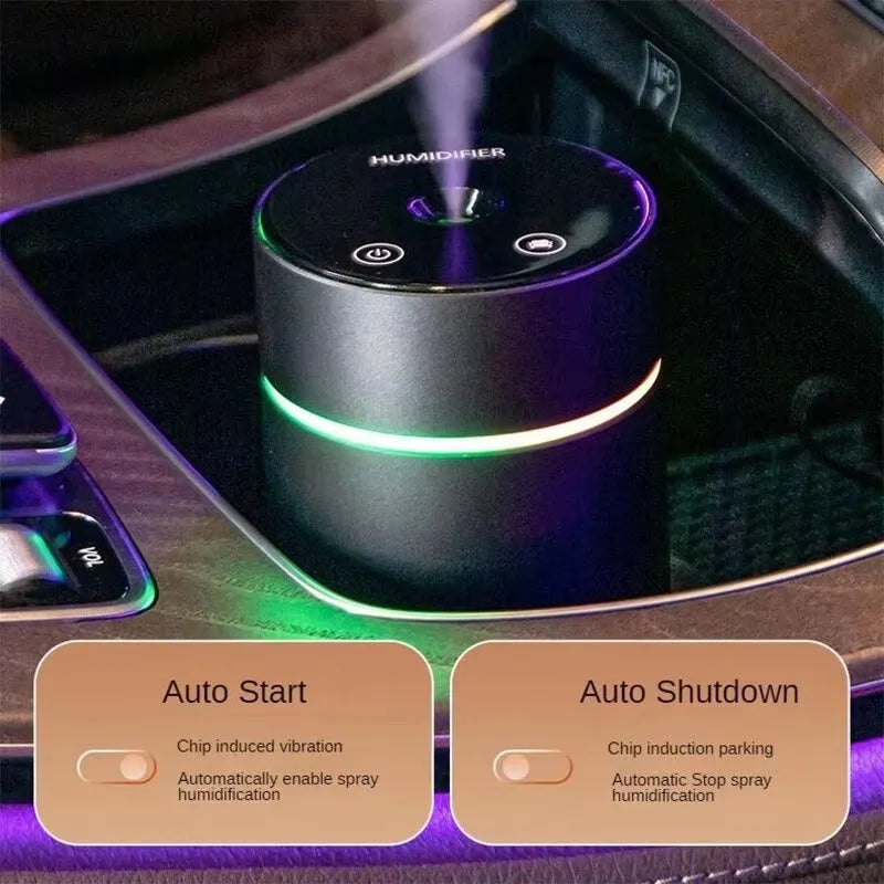 Black aluminium car humidifier and essential oil diffuser with night light on a desk next to USB cable.