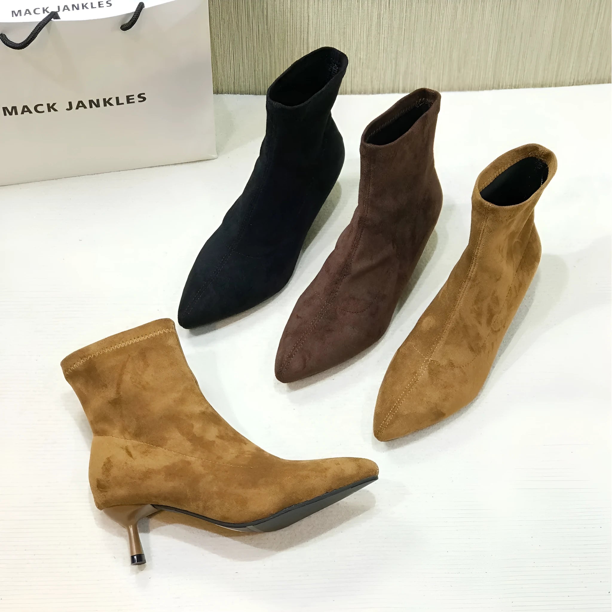 Black pointed toe stiletto heel ankle boots with a calf-high shaft on a neutral background.