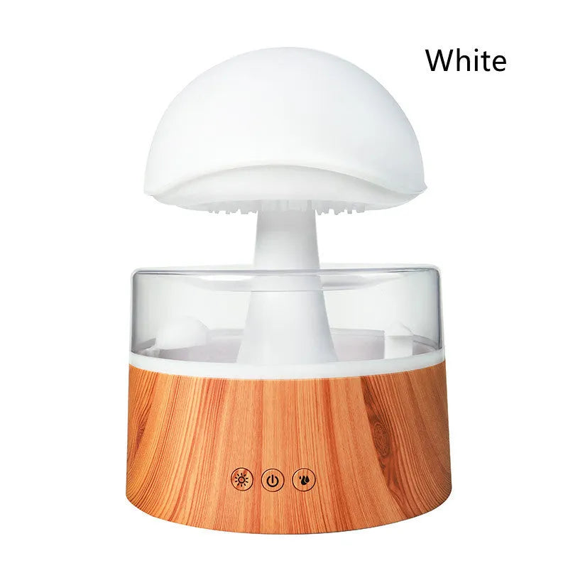 White cloud-shaped humidifier on a table emitting mist and showing coloured LED lights inside, with a remote control beside it.