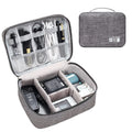 Black or grey waterproof travel cable organiser bag open to show mesh pockets and removable padded dividers.