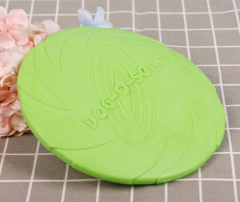 Dog training set with plastic frisbee and bite ring in orange and green colours on grass