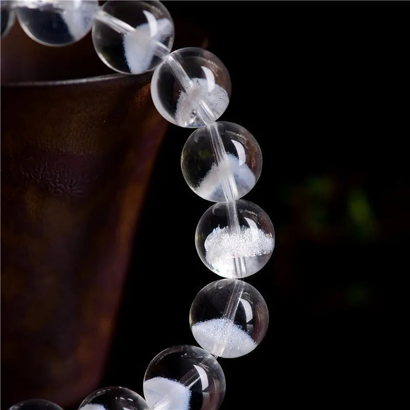 Women's white crystal pyramid bead bracelet with a silver ruyi charm on a white background.