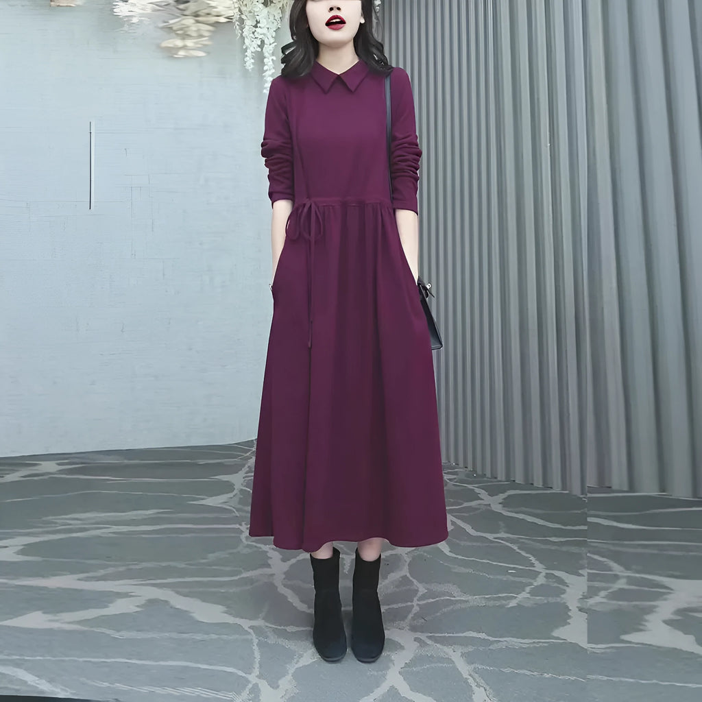 Purplish red women's plus size long sleeve dress with a long skirt, shown on a hanger.